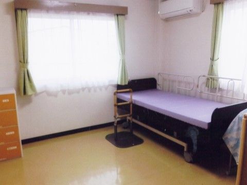二面採光でエアコン、収納チェスト、介護用ベッドが設置された個室