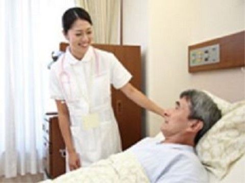 介護用ベッドに横になっている介助者に微笑みかける看護師