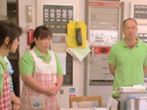 おそろいの黄緑色のポロシャツを着てミーティングをしているスタッフ