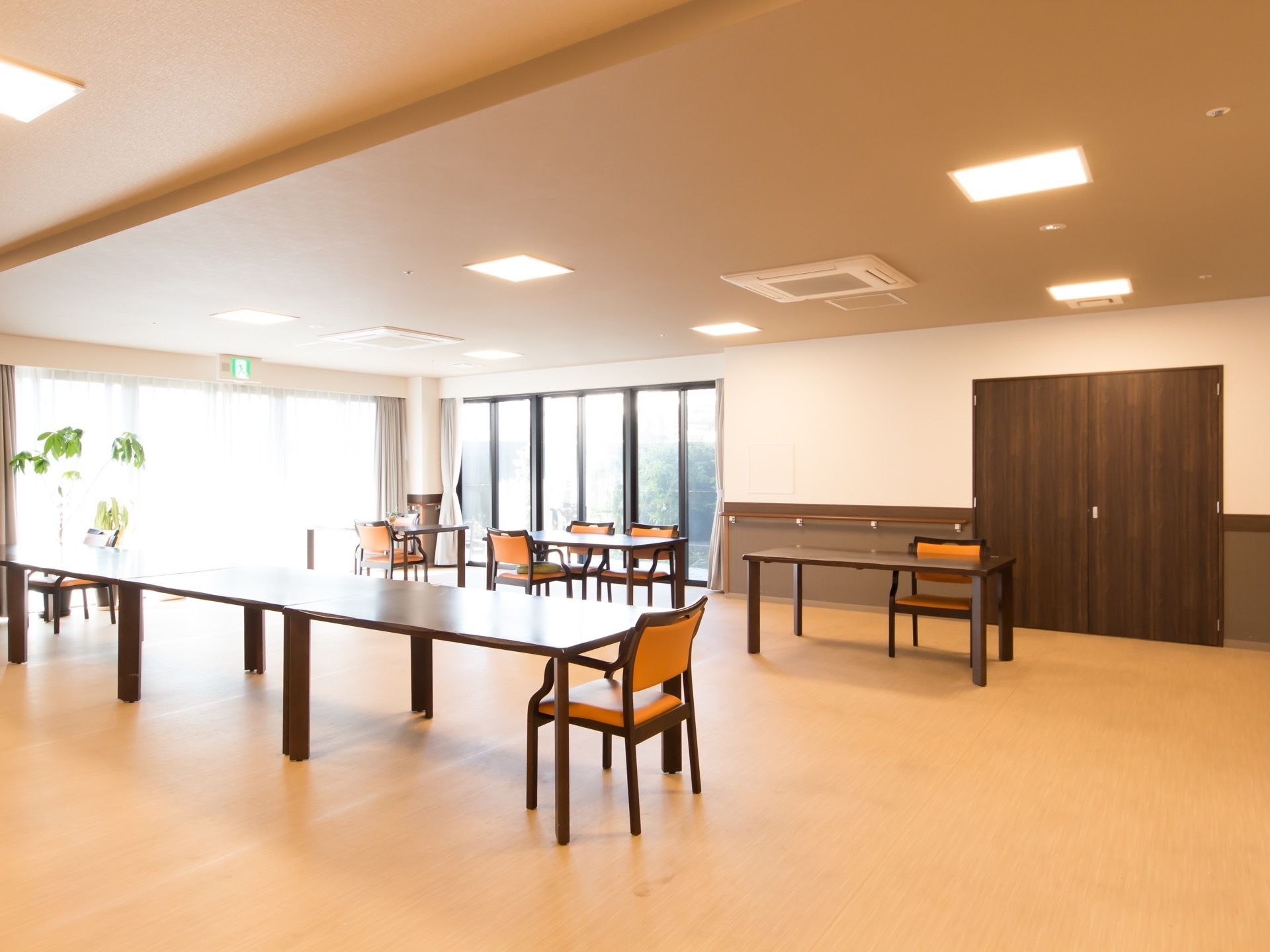 窓越しに屋外の緑を眺められる、開放的な共有スペースである。お食事や工作など、どんな場面にも対応できる大きいテーブルが並べられている。