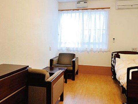 介護用ベッドとローテーブルを挟んで２脚のソファが設置されている個室