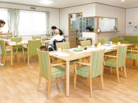 スタッフから食事の介助を受けている車いすの男性がいるダイニングルーム