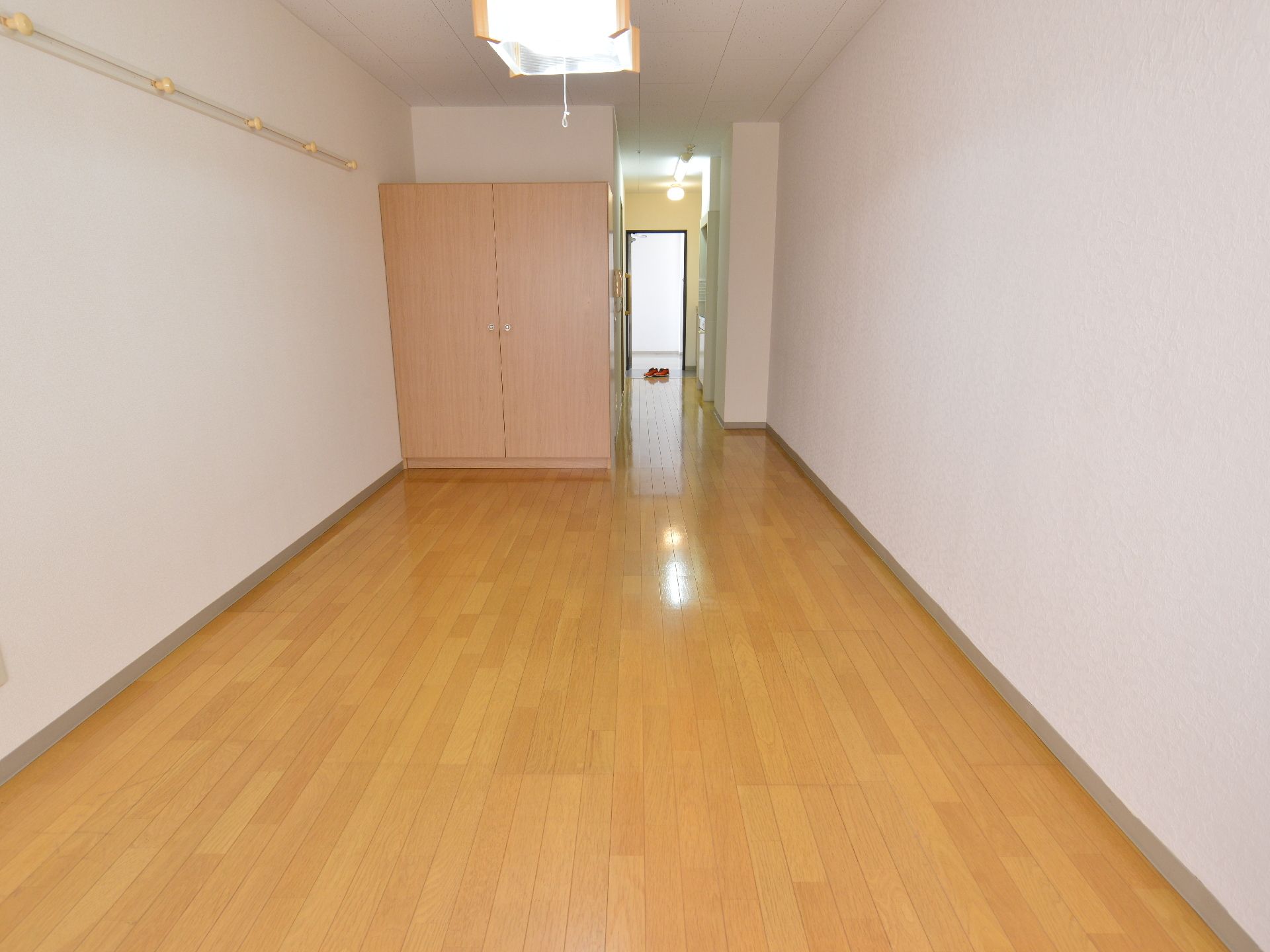 明るく広々とした居室。入り口付近にキッチンスペースとバストイレが設けられている。押し入れタイプの収納ボックスが設置されている。