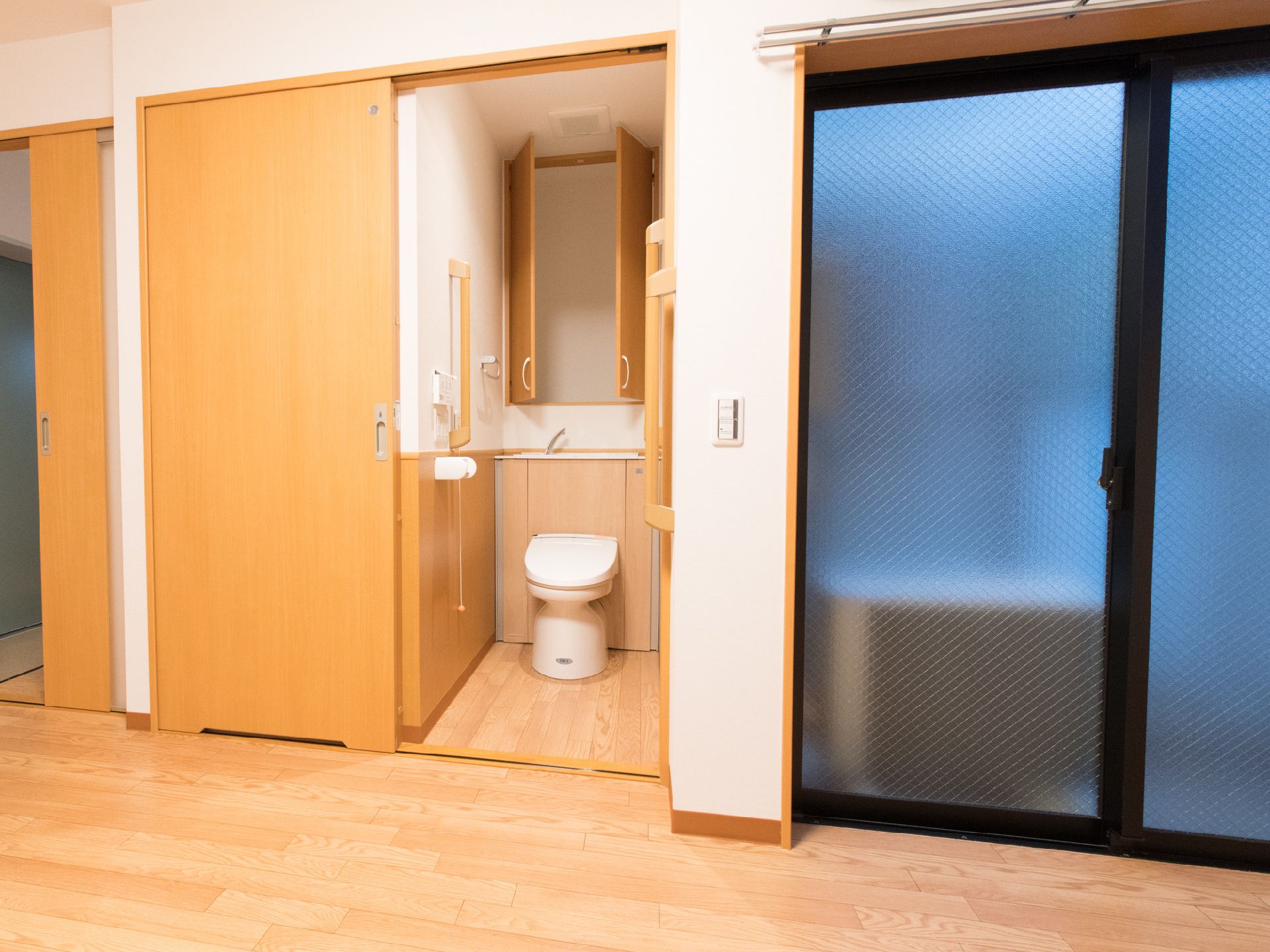 部屋とトイレの仕切りに段差はなく、ドアがスライド式なので部屋に開閉するスペースを作らない。並んでベランダがある。