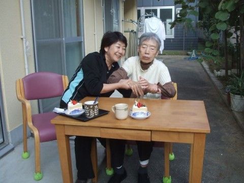 スタッフに介助を受けながらショートケーキを食べようとしている女性
