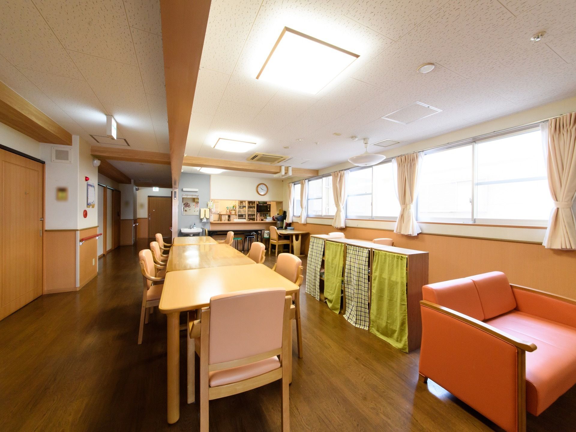窓側と通路側のテーブルのあいだに棚が置いてある。奥にキッチンカウンターがあり、そばに洗面台が設置されている。