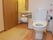 洋式トイレの出入り口付近に洗面台があり、肘掛付き手すりが片側について安全に使用できる。扉は大きなスライド式である。