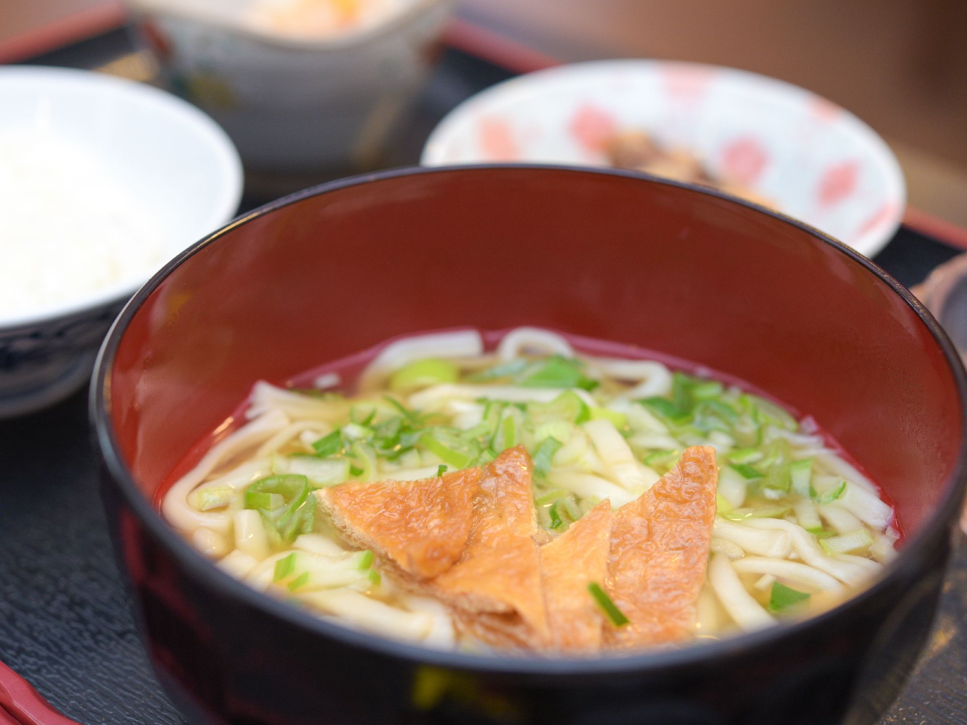 汁物としてうどんが提供されている。油揚げの乗ったきつねうどんでネギも散らされていてとても美味しそうなうどん。