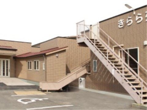 落ち着きある茶系の建物である。玄関の扉は白く分かりやすい。壁の上部に白い文字で施設名が書かれてある。