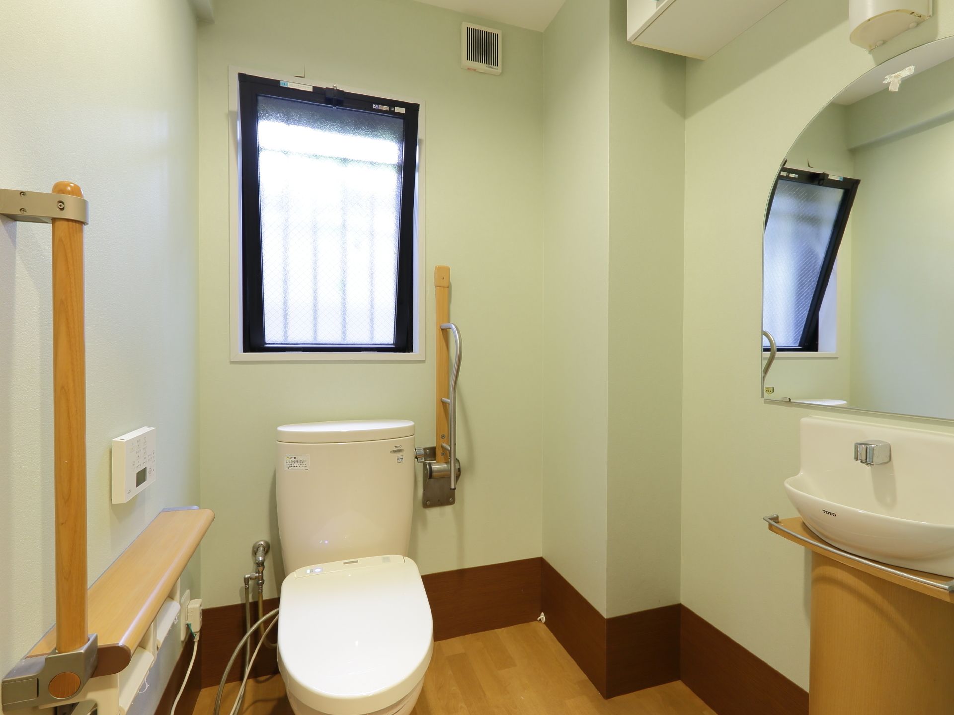 立ち上がり用の手すりが完備されたトイレである。温水洗浄機能付きの便座で、快適に利用することができる。