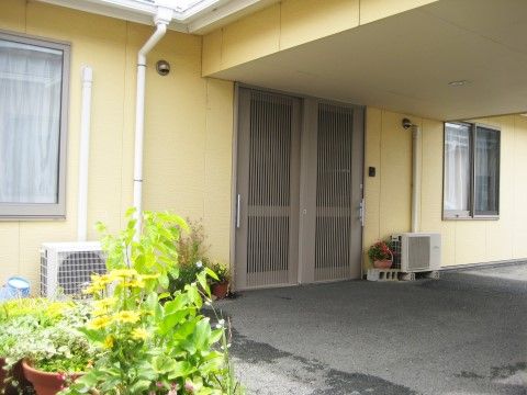 黄色い壁が印象的な玄関になっており、軒下のスペースがあり、雨や風の強い日でも安全に入室することができる。