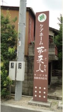 サービス付高齢者向住宅の施設の看板である。色は茶色で周囲とも違和感がない。高さがあるので見落とすことはない。