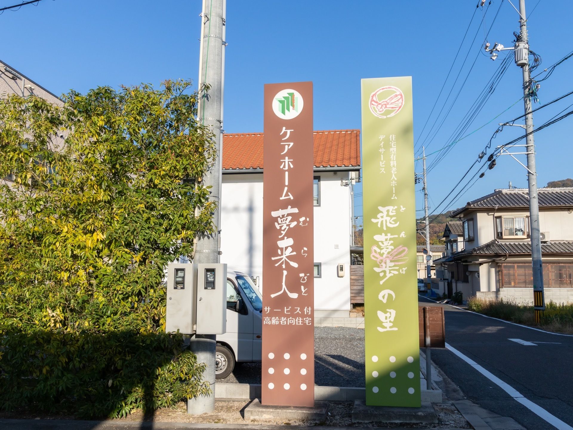 施設の敷地出入り口には、大きな看板が２本設置されている。それぞれに当施設と併設されているデイサービスの名前が書かれている。