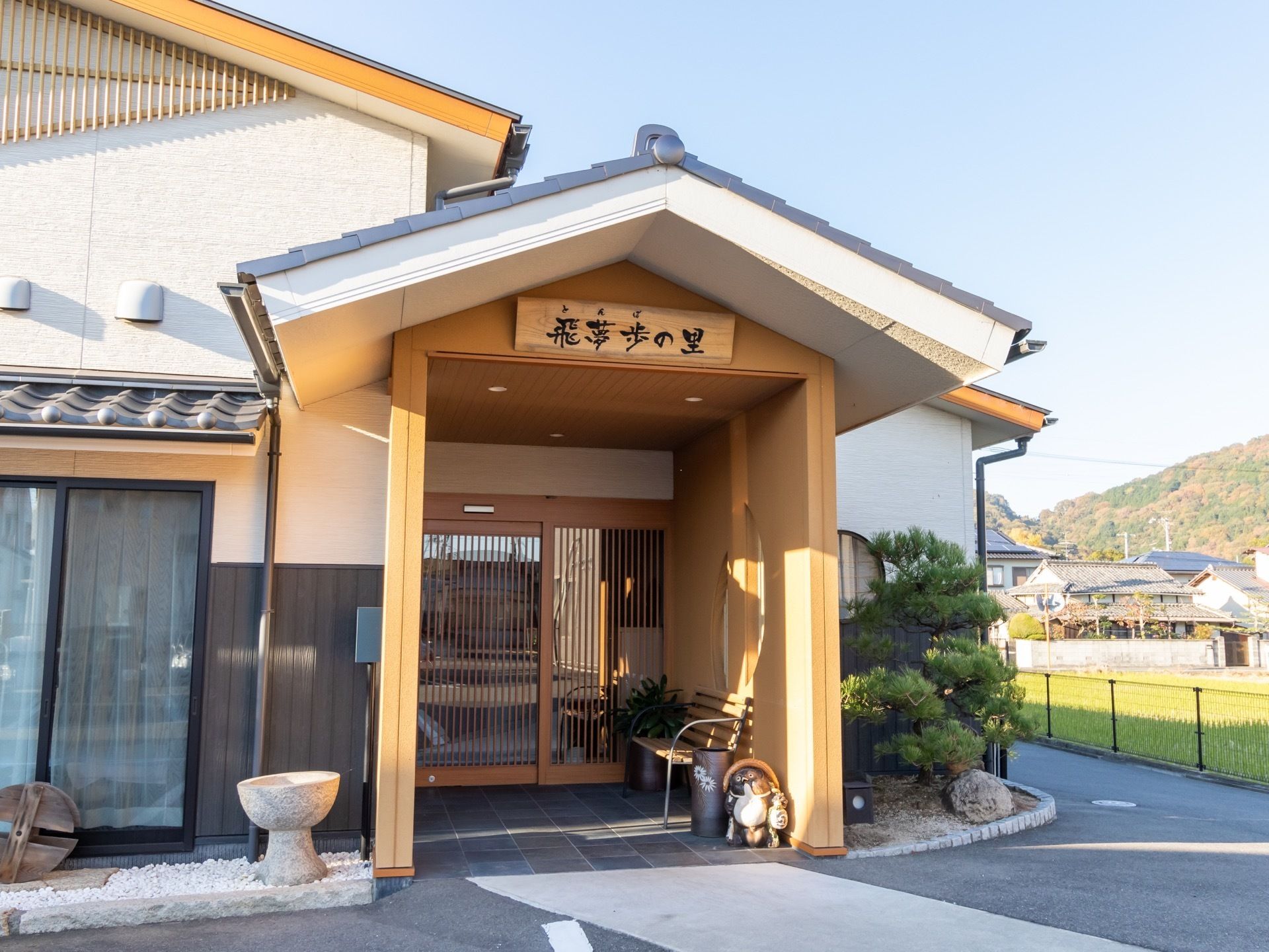 施設の周辺は山や田んぼがあり、自然豊かな環境になっている。建物は和風の構造で、三角の屋根が印象的である。