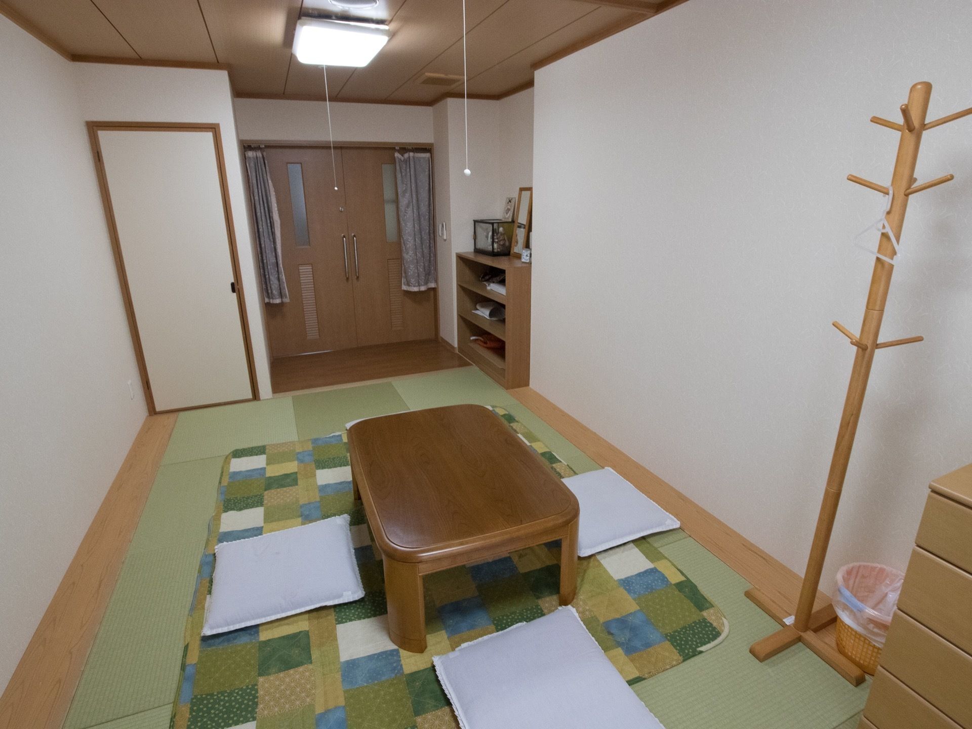 居室の一例。和室タイプもある。コート掛けと低いチェスト、３段の棚が置かれている。入口横には収納スペースがある。