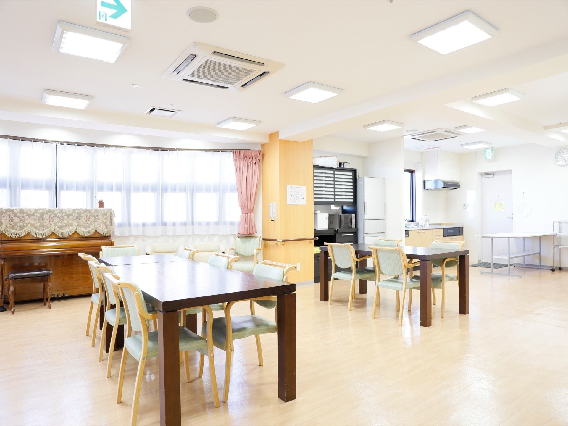 白い内装の食堂には、テーブルをセットし、窓際にはピアノを置いている。角にキッチンがあり、サイドには食器棚と冷蔵庫がある。