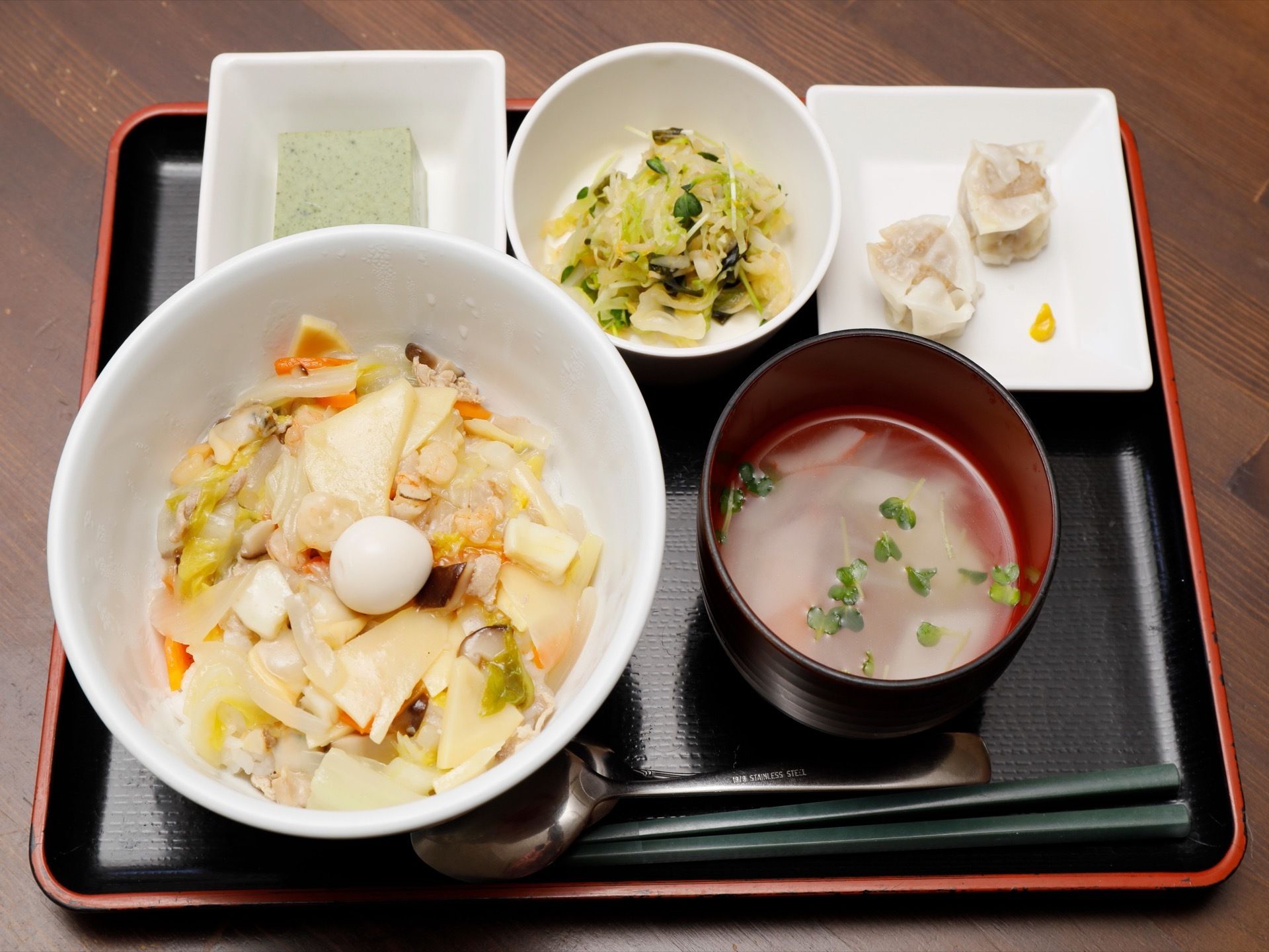 中華丼、お吸い物、小鉢が３品の栄養バランスを考慮した食事である。黒のトレイにセットし、箸とスプーンを添えている。