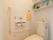 トイレの右側の壁には白色の棚が設置されている。時計やイミテーションの植物が置かれ、落ち着いた雰囲気となっている。