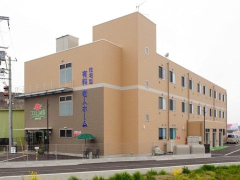 薄いオレンジ色で統一された外壁の3階建ての施設建物