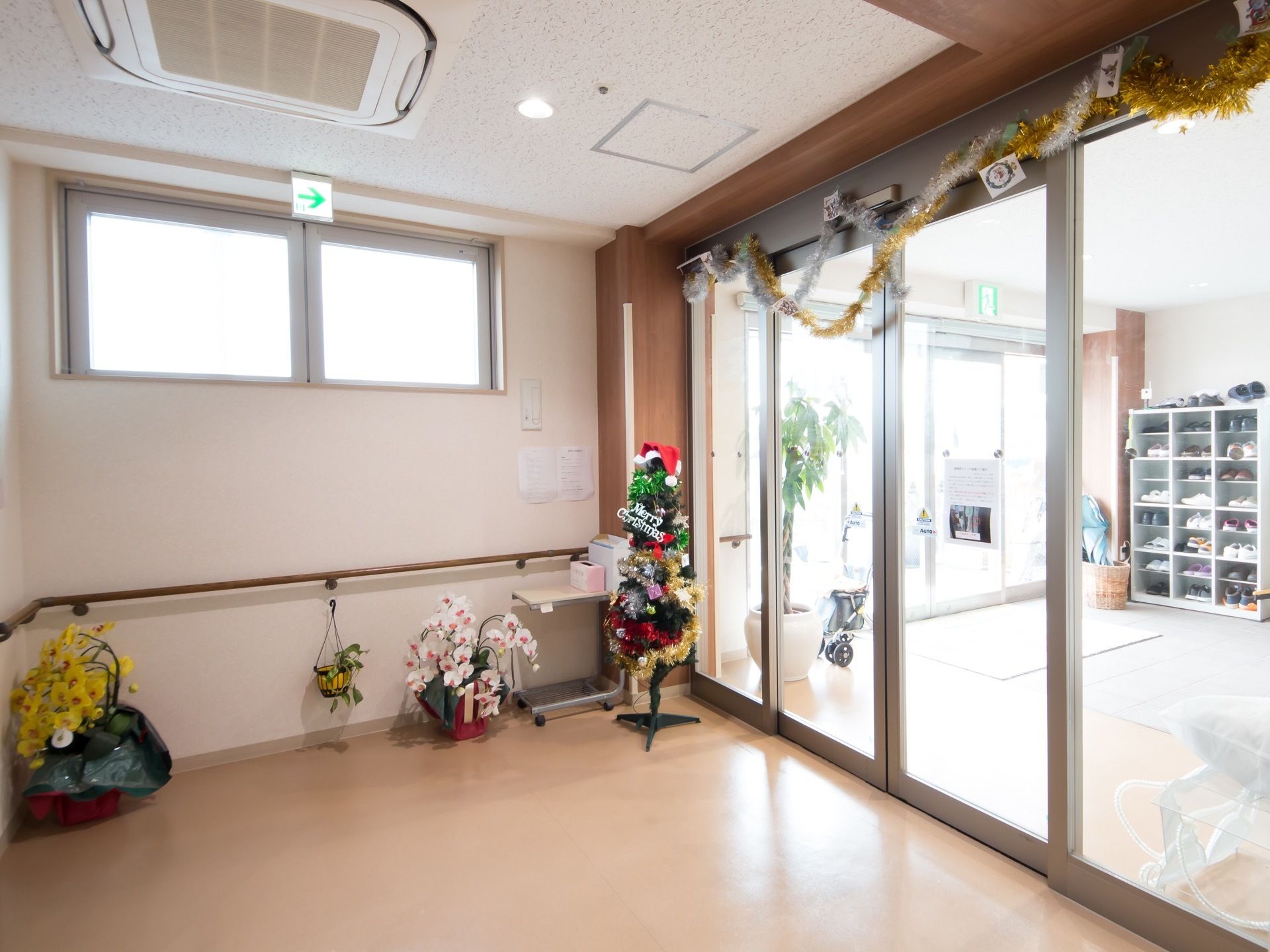 見通しの良い玄関の自動扉のそばには、クリスマスツリーや植木鉢に入った花などが置かれ飾りつけされている。