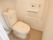 ご入居前の居室内のトイレの状態である。温水洗浄便座器が完備され、壁には呼び出しブザーや手すりが設置されている。