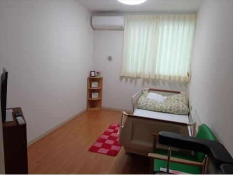 コーナー家具やベッド、1人掛けの椅子が置かれている居室