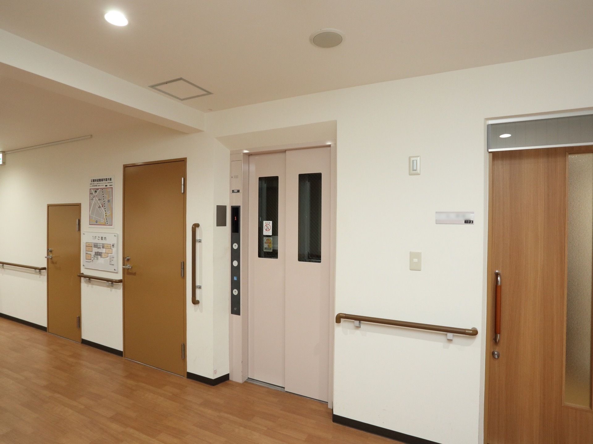 落ち着いた木目調の床で、壁は白色である。手すりが設置されている。淡いピンク色のエレベーターが完備されている。