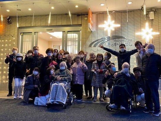イルミネーションの下で記念撮影をする高齢者