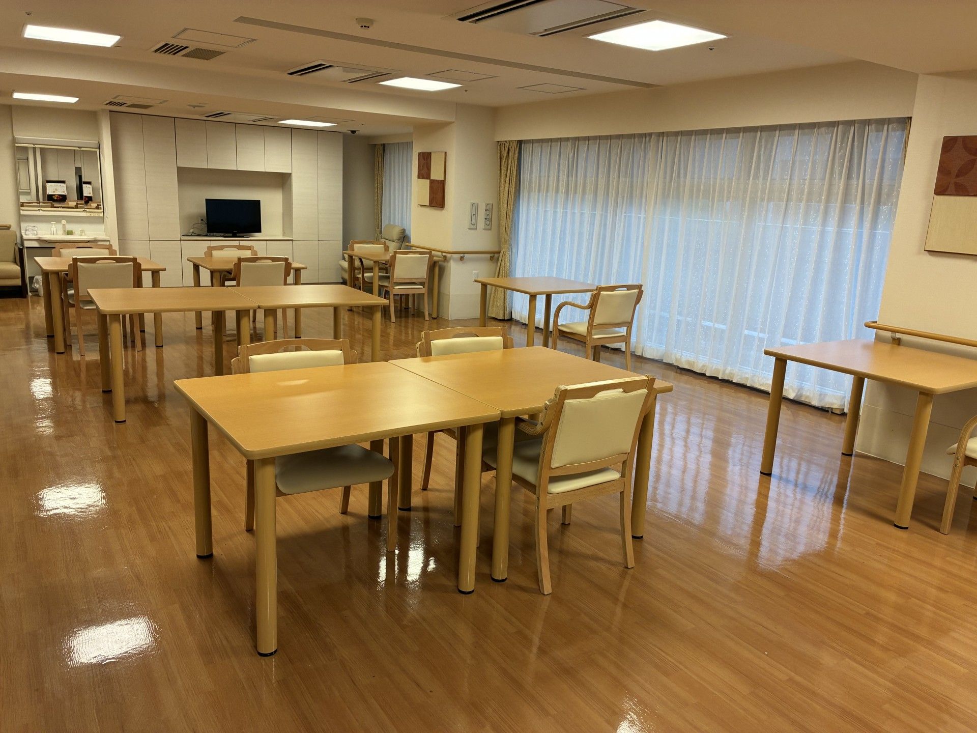 共有スペースの奥の壁に大型液晶テレビがあり、電源が入っている。右手にはキッチンがあり、カウンターになっている。