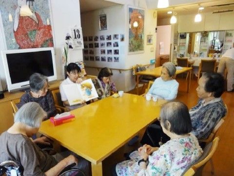 多目的室に集まって、絵本の朗読を楽しむ入居者の皆さん