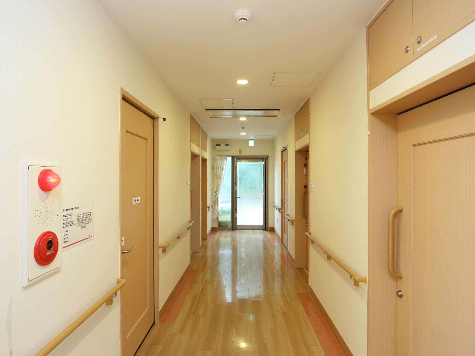 白木カラーで統一された廊下は非常口から差し込む光で明るい雰囲気。手すりが設置してあり、幅も広いので、歩行や車椅子での移動も安心。