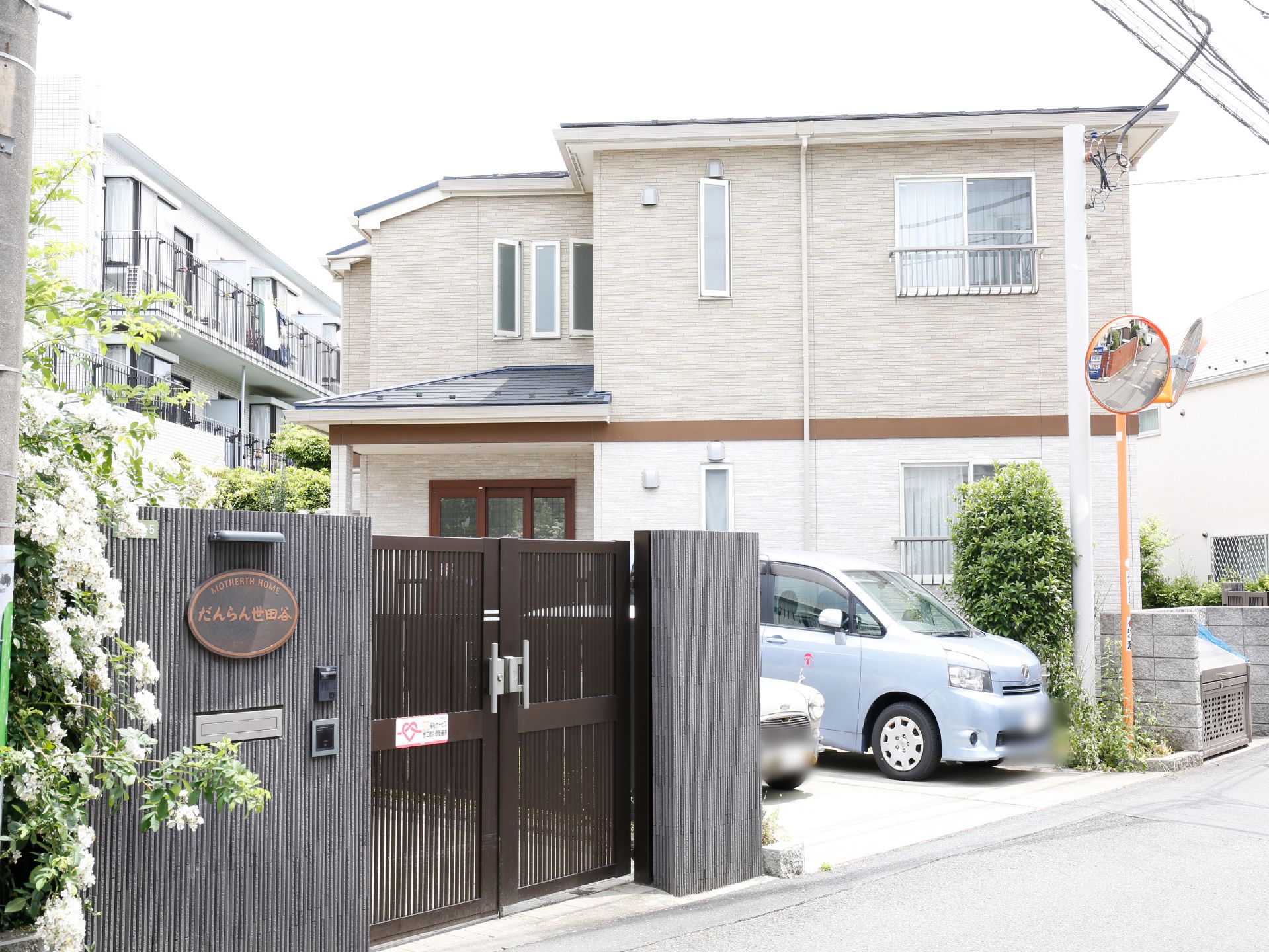 施設の入口は、黒を基調としたシックな印象である。横長で楕円形の形をした表札がある。インターホンが比較的低い位置に設置されている。