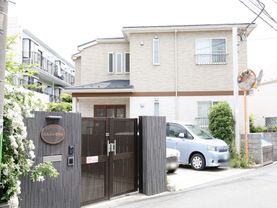 施設の入口は、黒を基調としたシックな印象である。横長で楕円形の形をした表札がある。インターホンが比較的低い位置に設置されている。