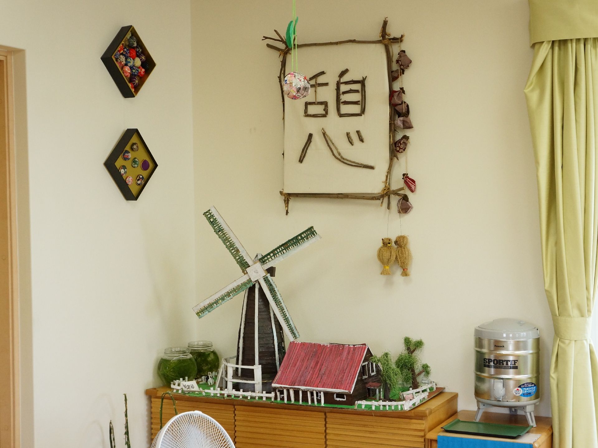 壁に掛けられたオブジェ。風車のジオラマ。様々な作品が沢山飾ってある。ウォータータンクも設置されている。