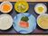 ご飯、メインのおかず、汁物、小鉢、漬物、フルーツが彩りよく、お盆に乗っている。希望者には3食提供している。