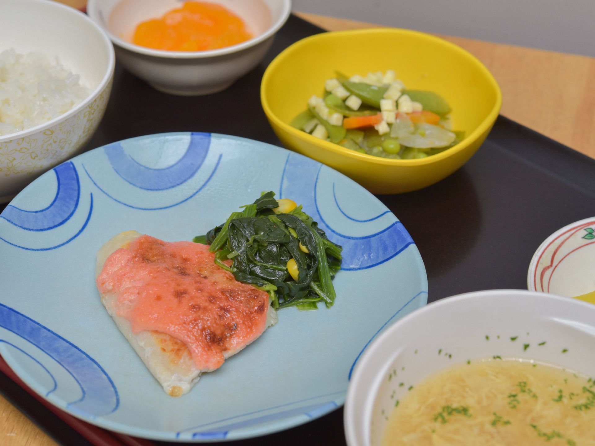 施設で提供されている食事。食事は、メインのおかずの他に、ご飯、汁物、小鉢、デザートがお盆に並んでいる。