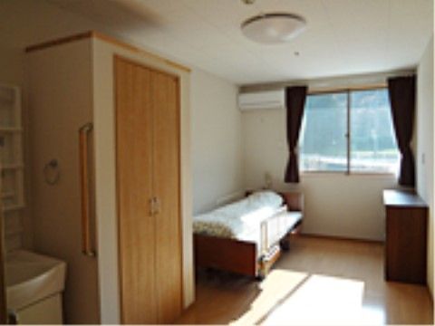 白い壁と木のフローリングの部屋である。室内には大きな収納スペースがある。洗面台の近くには安全面を考慮した手すりが設置されている。