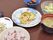 真ん中にはゴーヤチャンプルーがあり、他にはご飯・汁物・小鉢・サラダ・もう1品のおかずがある。食事は陶器で1品ずつ盛り付けられている。