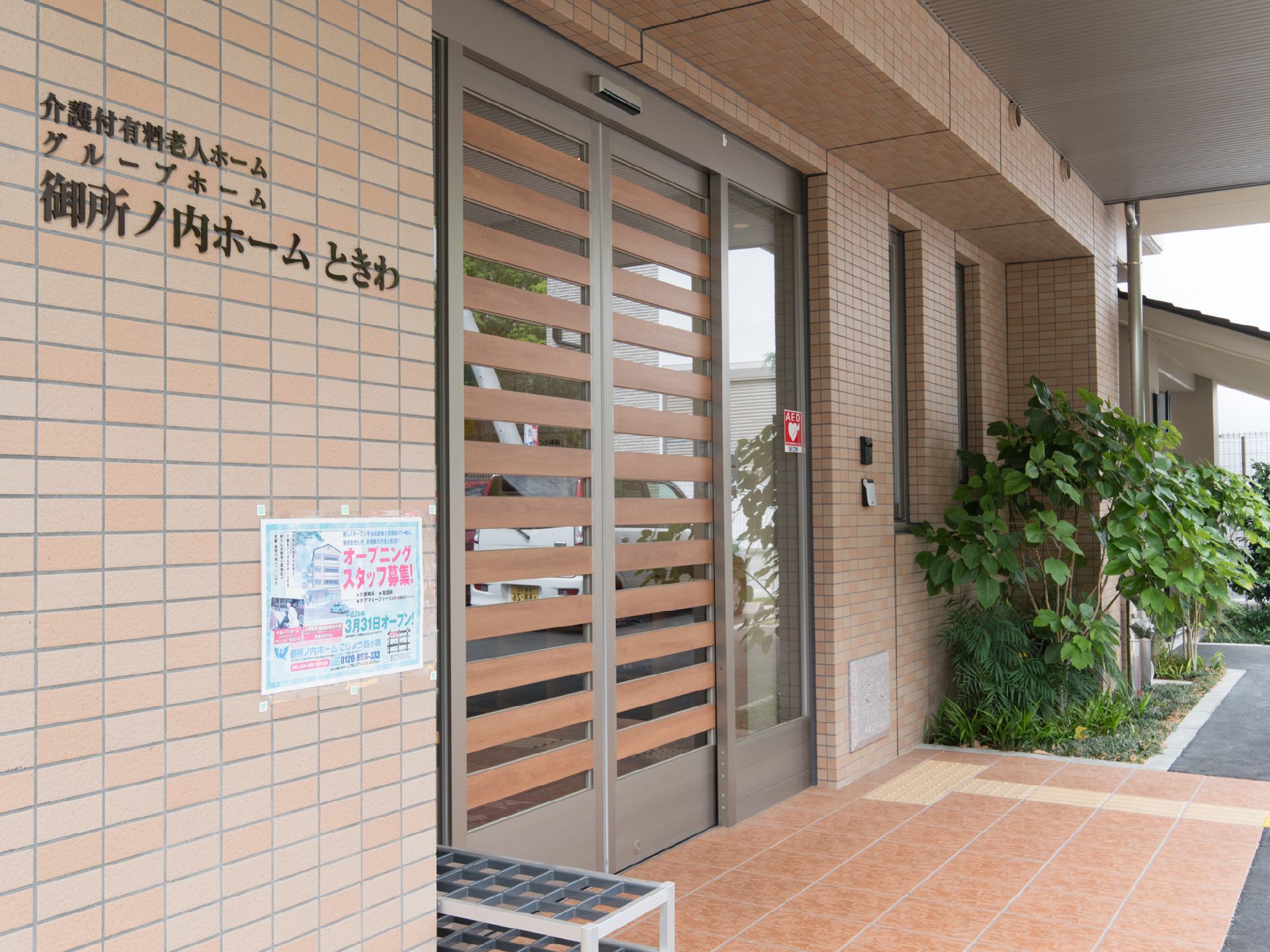 エントランス前には手入れが行き届いた植え込みがある。自動ドアと点字ブロックが完備により安心安全に移動ができる。