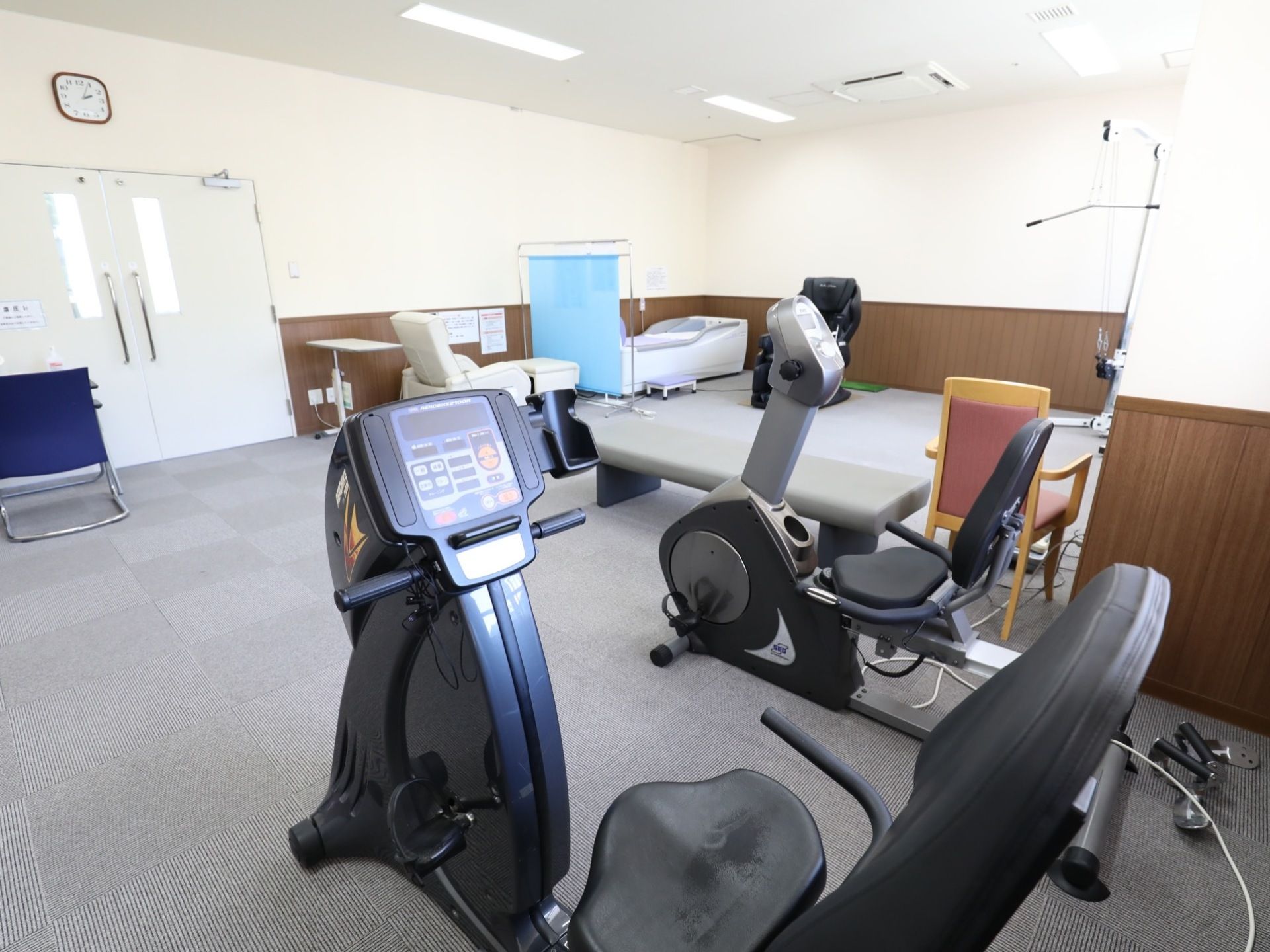 カーペット敷きの広い部屋には、体を動かして運動能力を鍛える器具が数多く設置されている。座って足を鍛える器具もある。