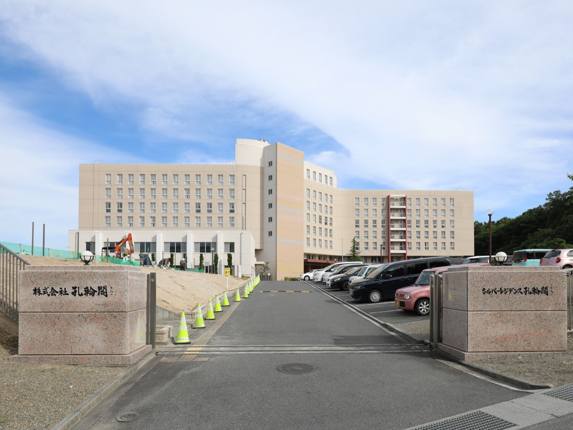 施設のそばには広い駐車場がある。駐車場の入口には石で作られた門があり、門には施設名と運営会社名が刻まれている。