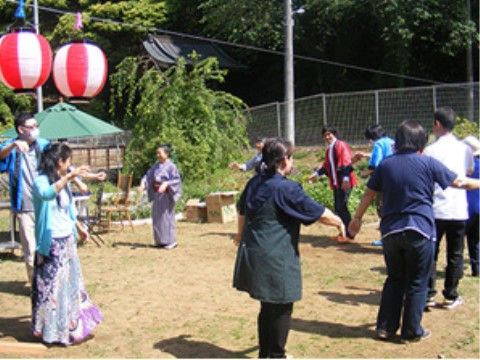 近くの公園の提灯がある盆踊り会場で、踊りを楽しむご入居者様と職員