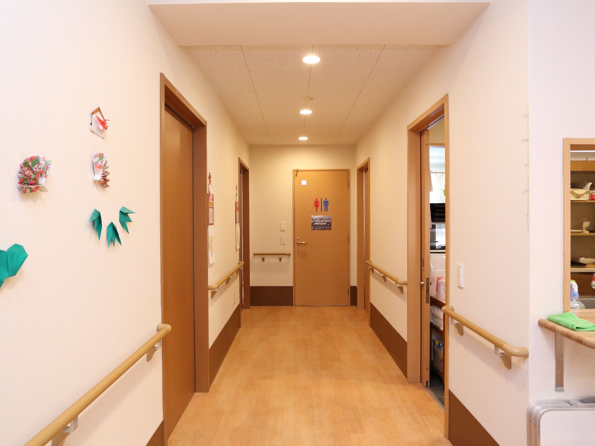 廊下の突当りが男女兼用のトイレ。居室のそばにあるので近くて便利。両側の壁には手摺があるので移動が安心。