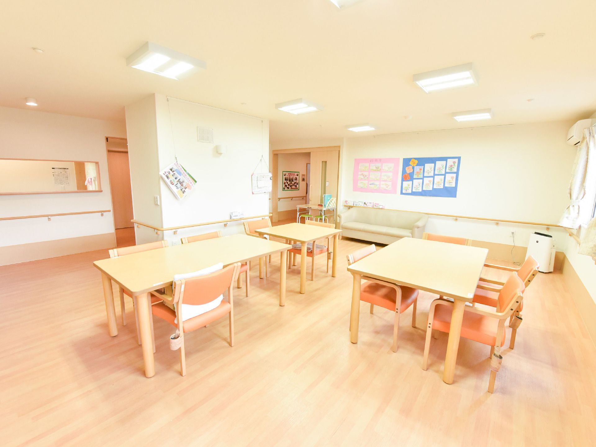 広い談話室に広いテーブルと椅子が広い間隔を開けて置かれている。車いすの移動が楽。手すりがありバリアフリーで安心。