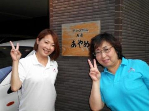 当施設の看板の前で仲良くピースサインをする二人の職員