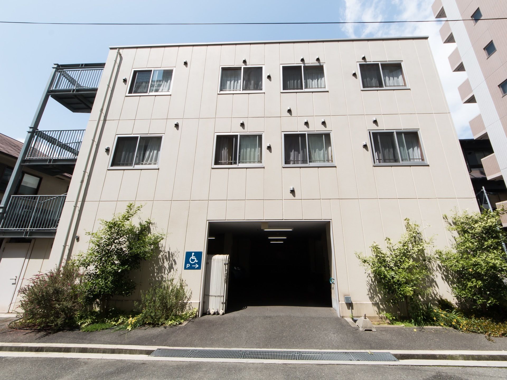 ３階建て施設建物の１階側面に駐車スペースへの入口が設けられている。車椅子をご利用の方専用のレーンが設置されている。