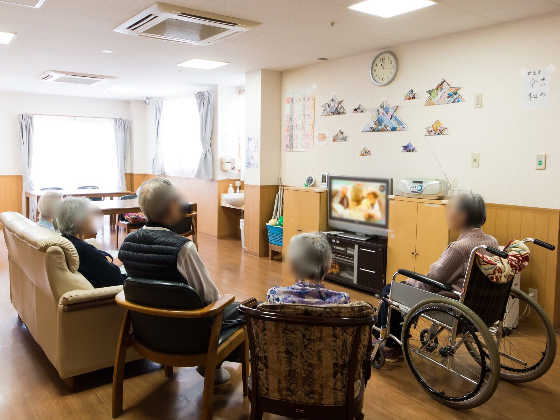 新元号となった端午の節句頃の共有スペースの様子。数人の入居者様が集い、椅子に腰掛けてテレビ鑑賞を楽しんでいる。