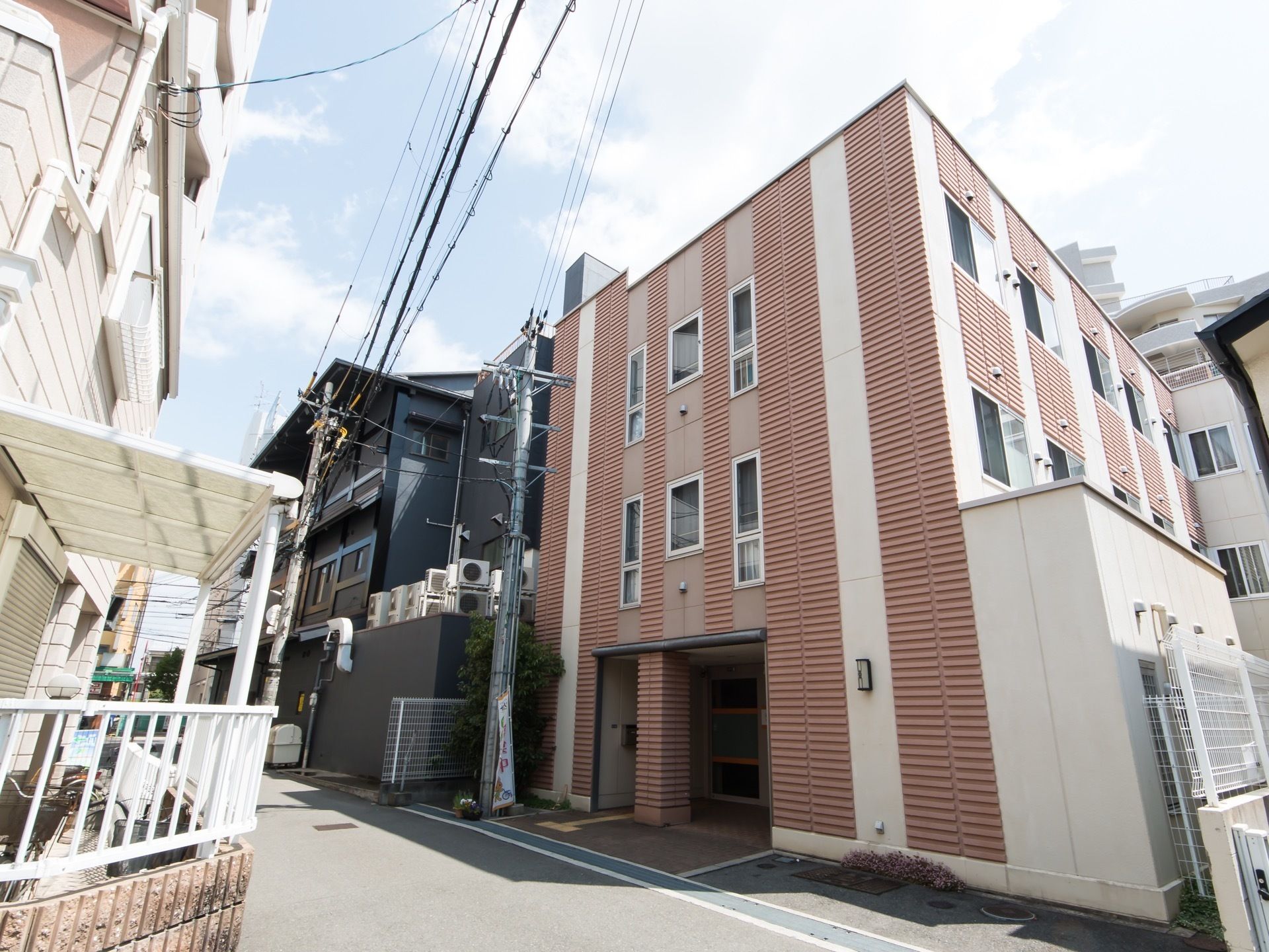 住宅街に立地する３階建ての施設の様子である。とても日当りが良い。入口付近に点字ブロックが設置されている。