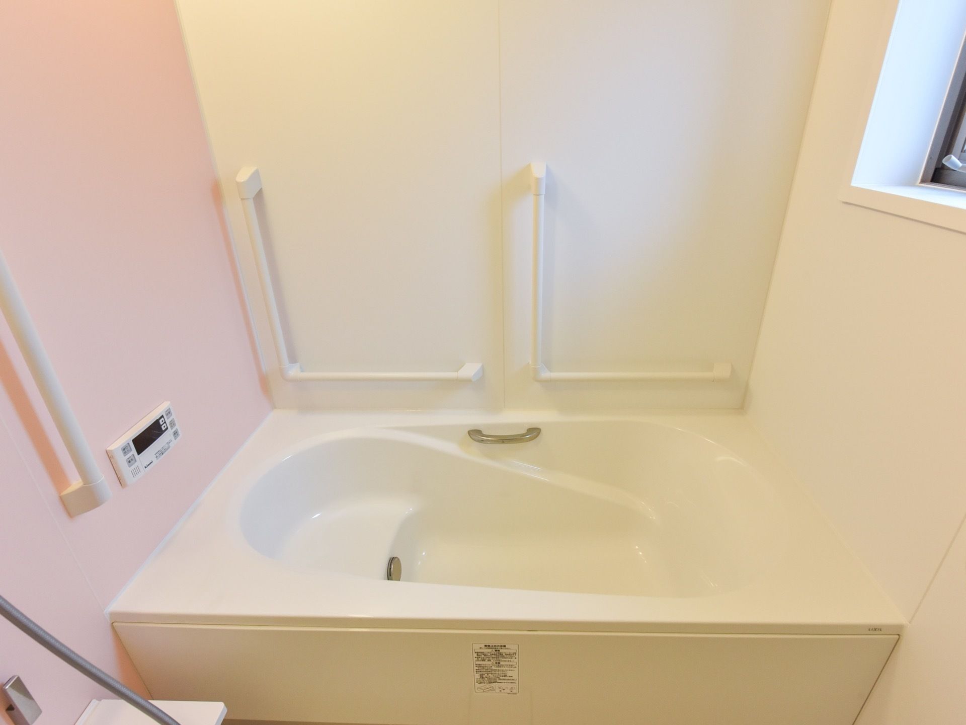 白を基調とした浴室で清潔感がある。手すりが各所に付いていて、入居者様は安心して利用することができる。