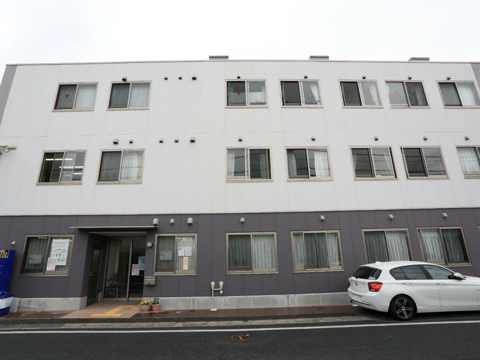 駐車スペースがあり、大きな窓に面した居室がある当施設の外観